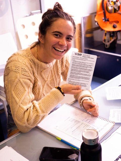Divemaster en classe souriant avec sa plaquette - © Dune