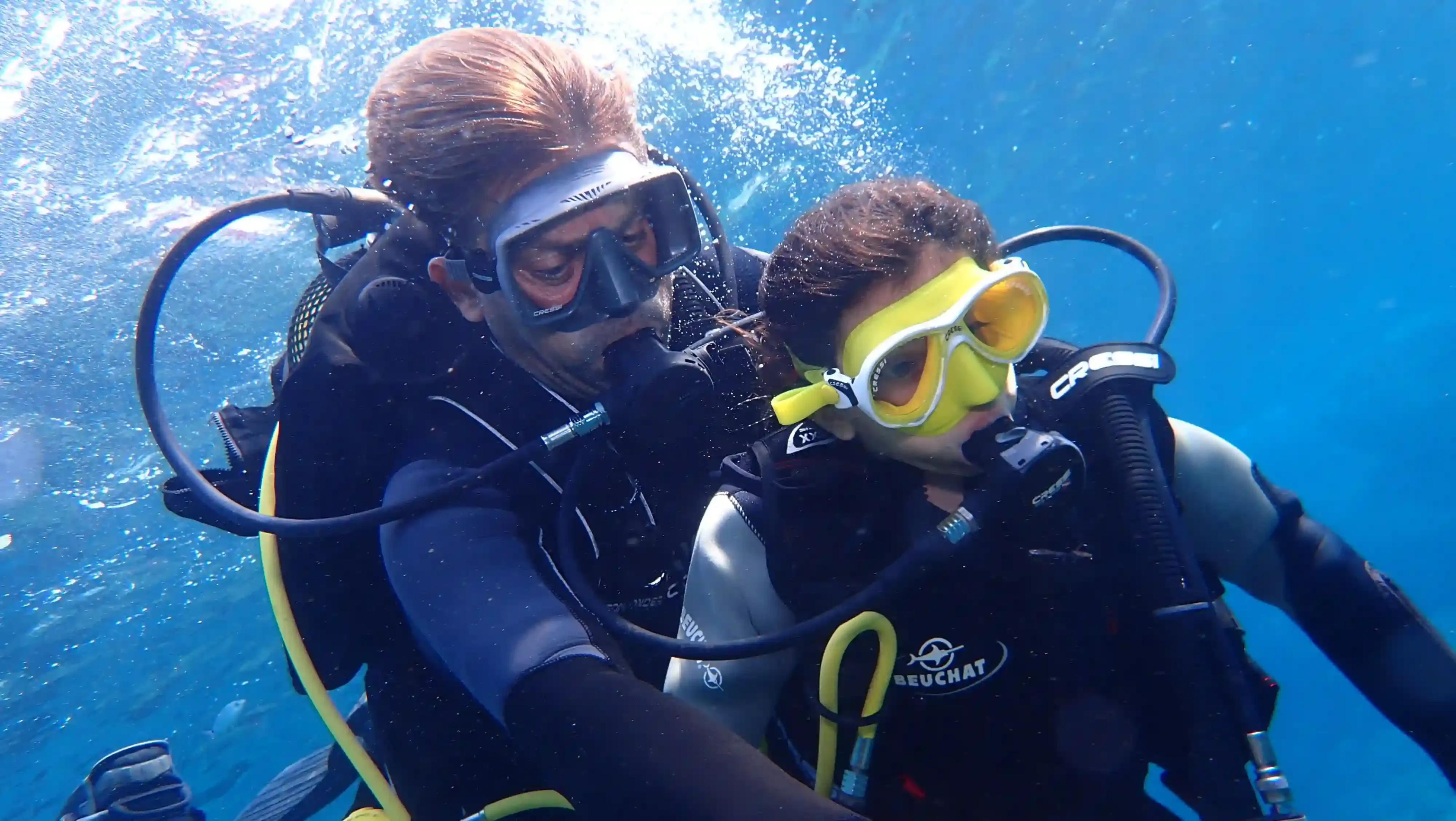 Niña acompañada de un Instructor haciendo burbujas - © Dune