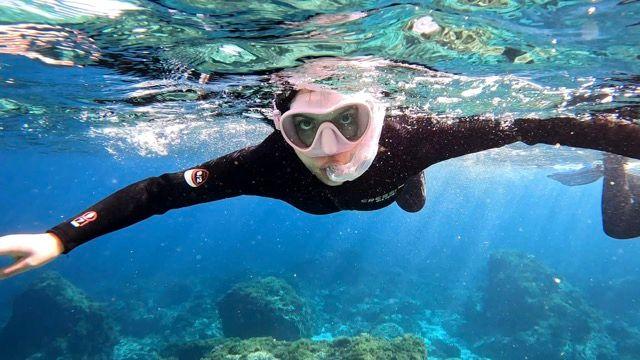 Young girl on the surface with her snorkel in mouth - © Dune